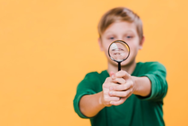 Front view of boy holding magnifying glass