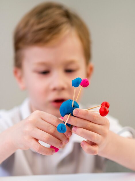 Front view boy playing with colorful atoms game