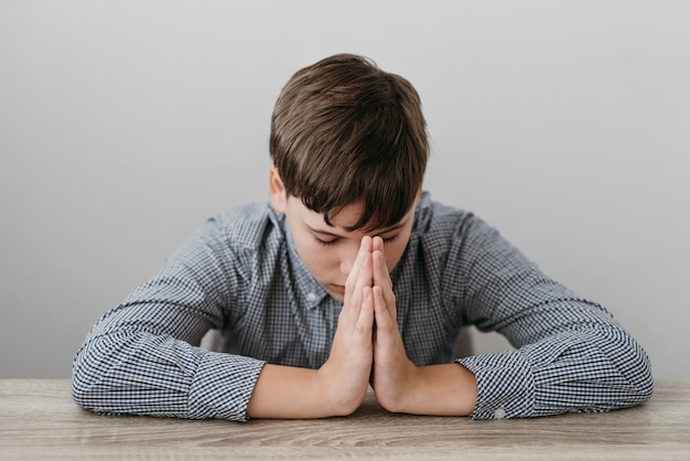 Free photo front view boy praying at the table