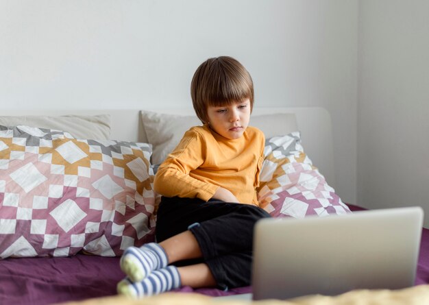 Front view boy sitting in bed and learning