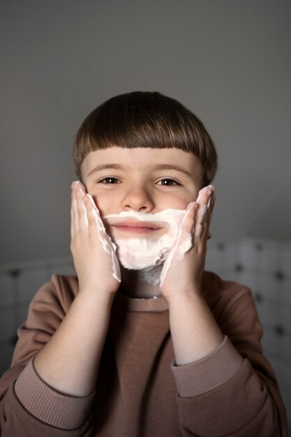 Front view boy using shaving cream