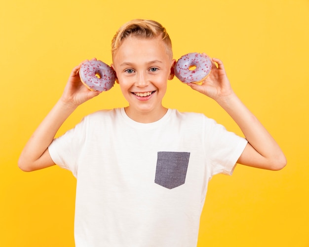 Free photo front view boy with doughnuts at his ears