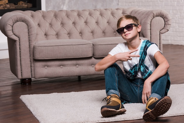 Free photo front view of boy with sunglasses sitting on floor