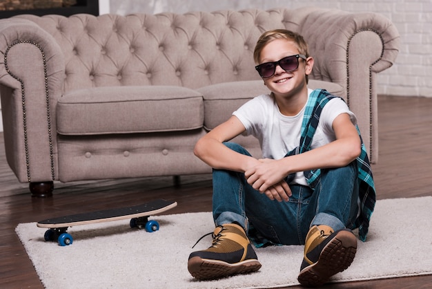 Free Photo front view of boy with sunglasses sitting on floor