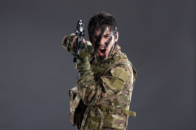 Free photo front view brave soldier fighting in camouflage with machine gun dark wall