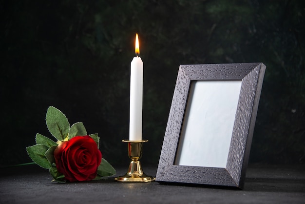 Free photo front view of burning candle with picture frame on dark surface