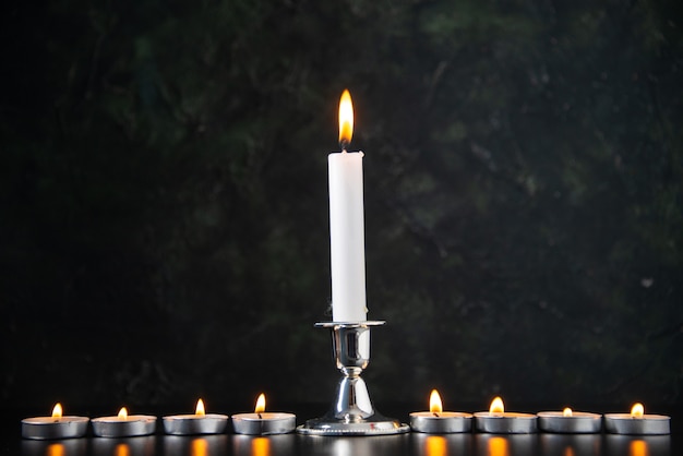 Front view of burning candles as a memory for fallen on black surface