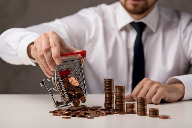 Free photo front view of businessman spilling shopping cart of coins