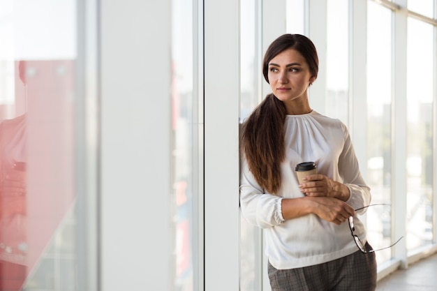 Front view of businesswoman posing with cup of coffee