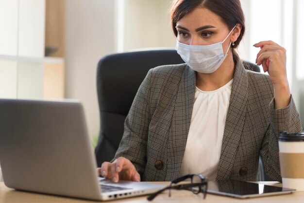 Front view of businesswoman working with face mask at desk