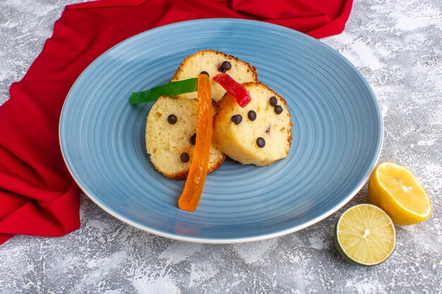 Front view of cake slice inside blue plate with choco chips and marmalade on rustic grey desk cake biscuit sweet bake pie