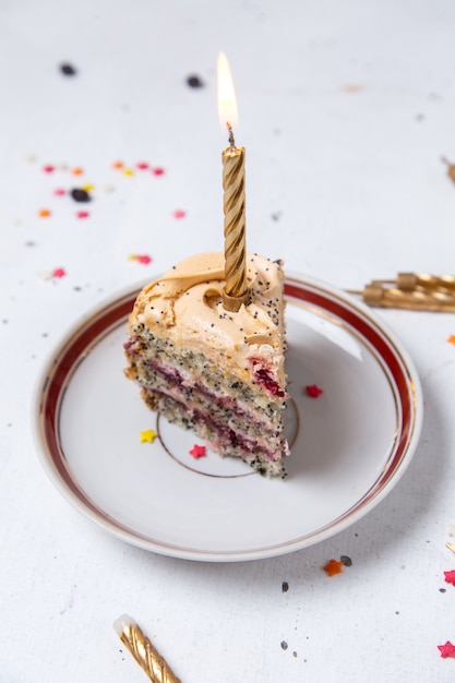 Free photo front view of cake slice inside plate with candle on the light surface