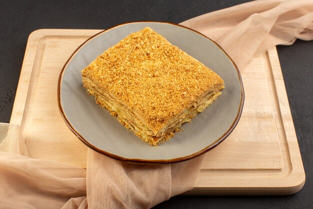 A front view cake slice yummy and baked inside plate on the wooden desk and dark cake biscuit sugar sweet