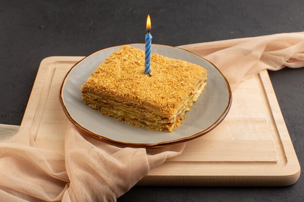 A front view cake slice yummy and baked inside plate on the wooden desk and dark cake biscuit sugar sweet