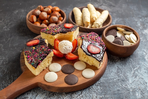 Front view cake slices with nuts and cookies on dark background