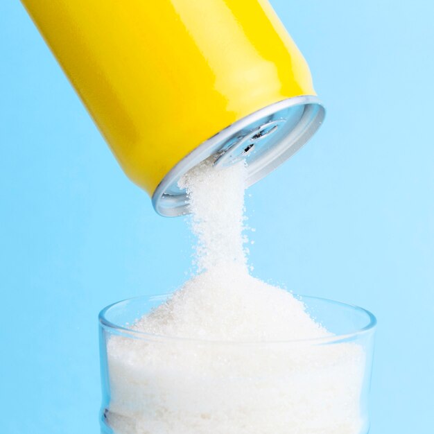 Front view of can pouring sugar in glass