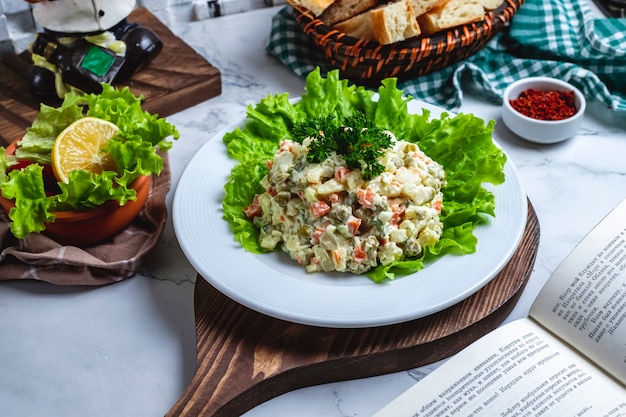 Free photo front view capital salad on lettuce with bread and a slice of lemon on the table