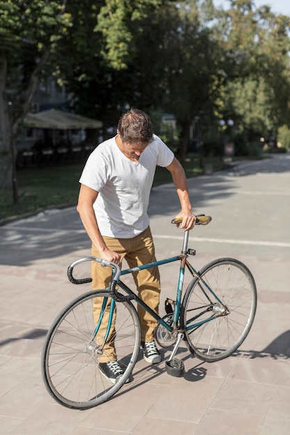 Free photo front view casual male checking his bicycle