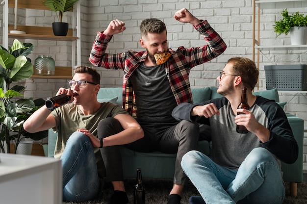 Free photo front view of cheerful male friends having pizza and watching sports on tv