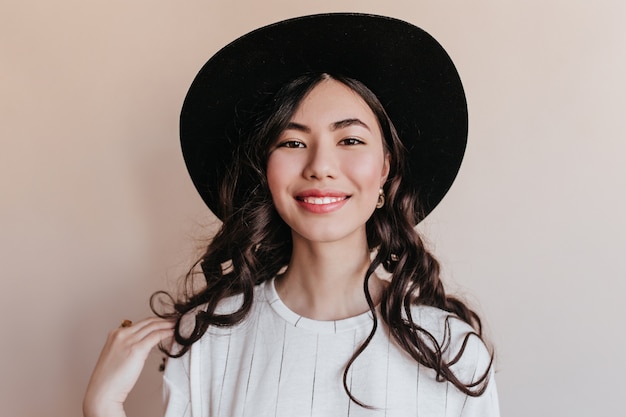 Front view of cheerful smiling asian woman. Studio shot of happy korean woman wearing black hat.