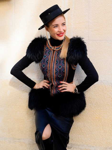 Free photo front view of cheerful woman with bright red lipstick on lips wearing in hat leather skirt glamour vest which adorned by eco fur and