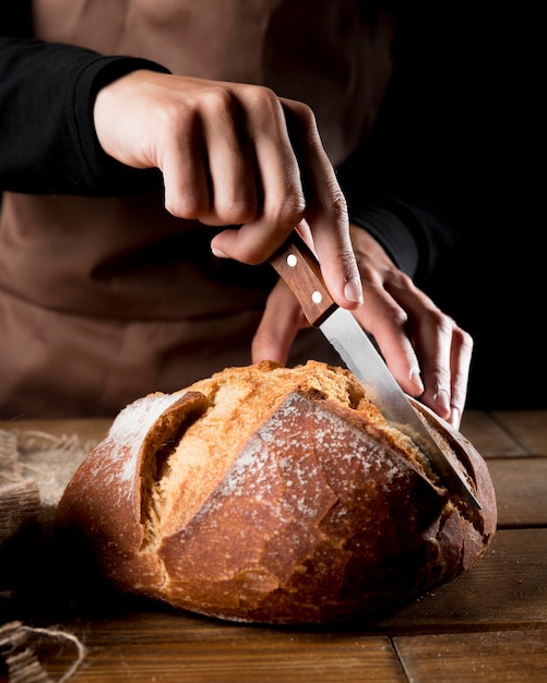 Free photo front view of chef cutting delicious bread