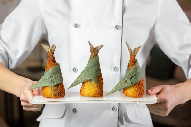 Free photo front view of chef holding a plate with fish