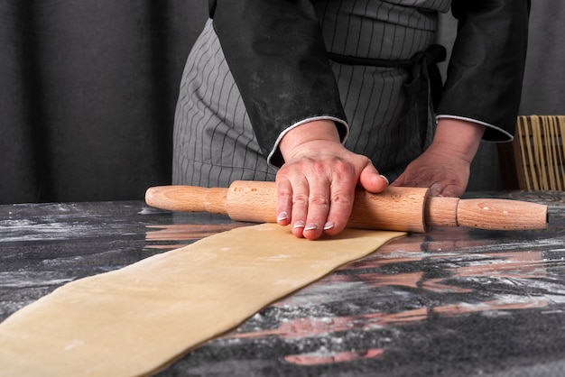 Front view of chef rolling dough