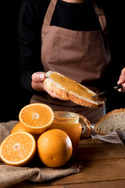 Front view of chef spreading orange marmalade on bread