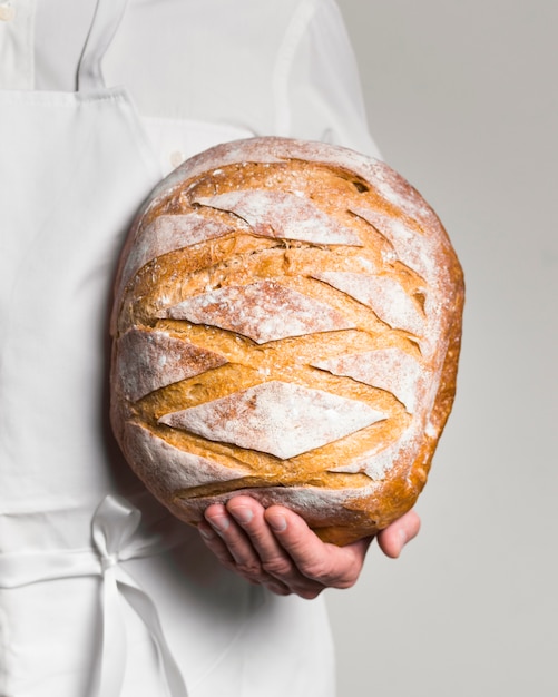 Free photo front view chef wearing white clothes holding a bread