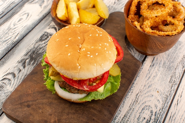 Free photo a front view chicken burger with cheese and green salad potatoes on the wooden desk and grey surface