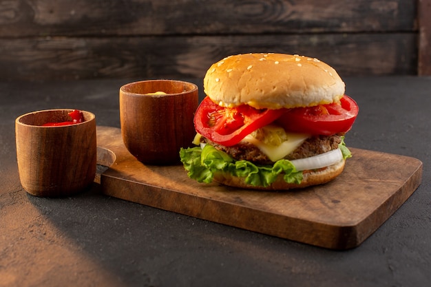 A front view chicken burger with cheese and green salad on the wooden desk and sandwich fast-food meal