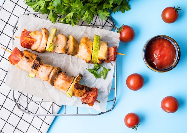 Free Photo front view chicken skewers on parchment paper with cherry tomatoes and sauce