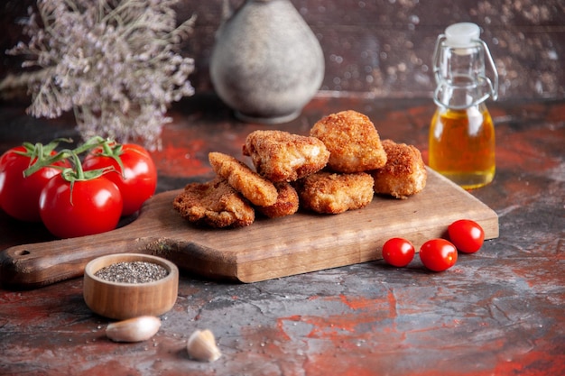 Front view chicken wings on cutting board with fresh tomatoes dark background burger food dinner meal sandwich lunch salad horizontal