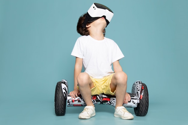 A front view child boy cute adorable sweet playing vr on segway on the blue floor