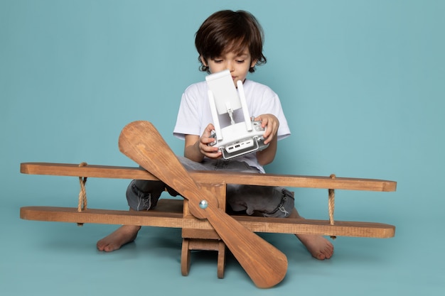 Free photo front view child boy in white t-shirt holding remote controller on blue