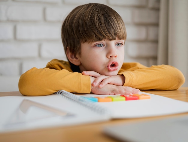 Front view of child at desk learning from laptop