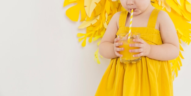 Front view of child drinking juice from glass with straw