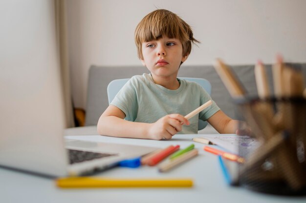 Front view of child at home learning form laptop