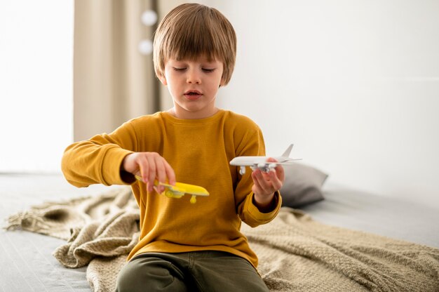 Front view of child playing with airplane figurines