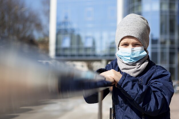 Front view of child posing outside with medical mask