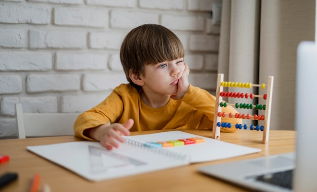 Free photo front view of child with abacus learning from laptop at home