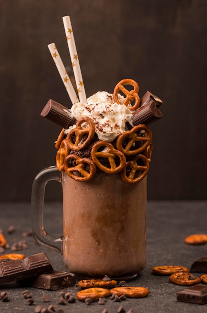 Free photo front view of chocolate milkshake with pretzels and straws