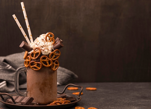 Free photo front view of chocolate milkshake with straws and pretzels