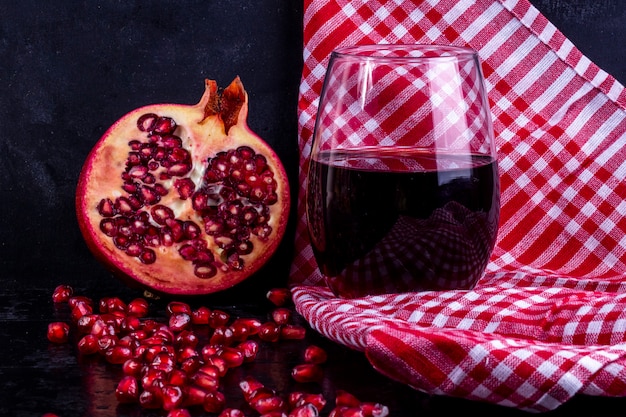 Front view chopped pomegranate with pomegranate juice in a glass on a red towel