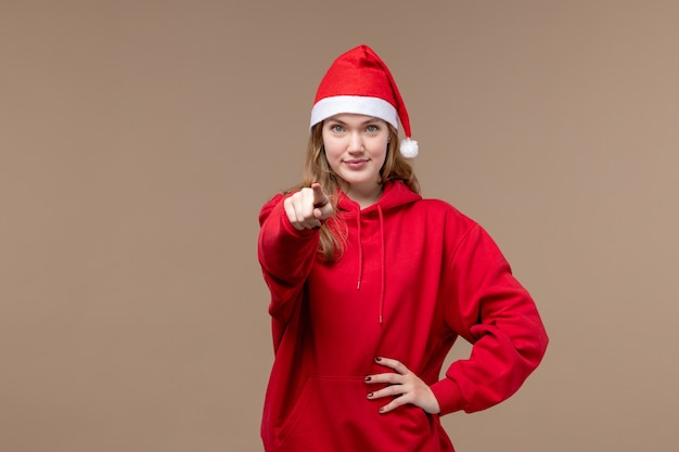 Front view christmas girl smiling and pointing on brown background woman holiday christmas