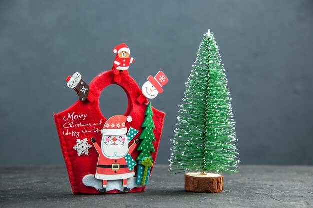 Front view of christmas mood with decoration accessories on new year gift box and xsmas tree on dark surface