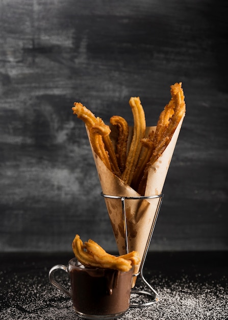 Front view churros in wrapping paper and chocolate