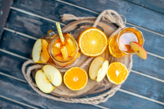 Free photo front view cocktail cut oranges and apples on wood board on dark isolated background