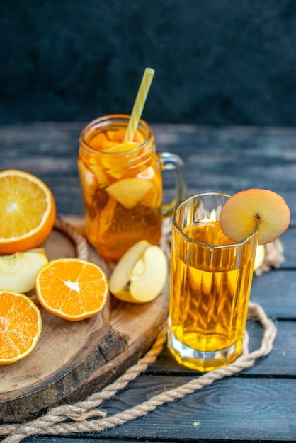 Front view cocktail cut oranges and apples on wood board on dark isolated background